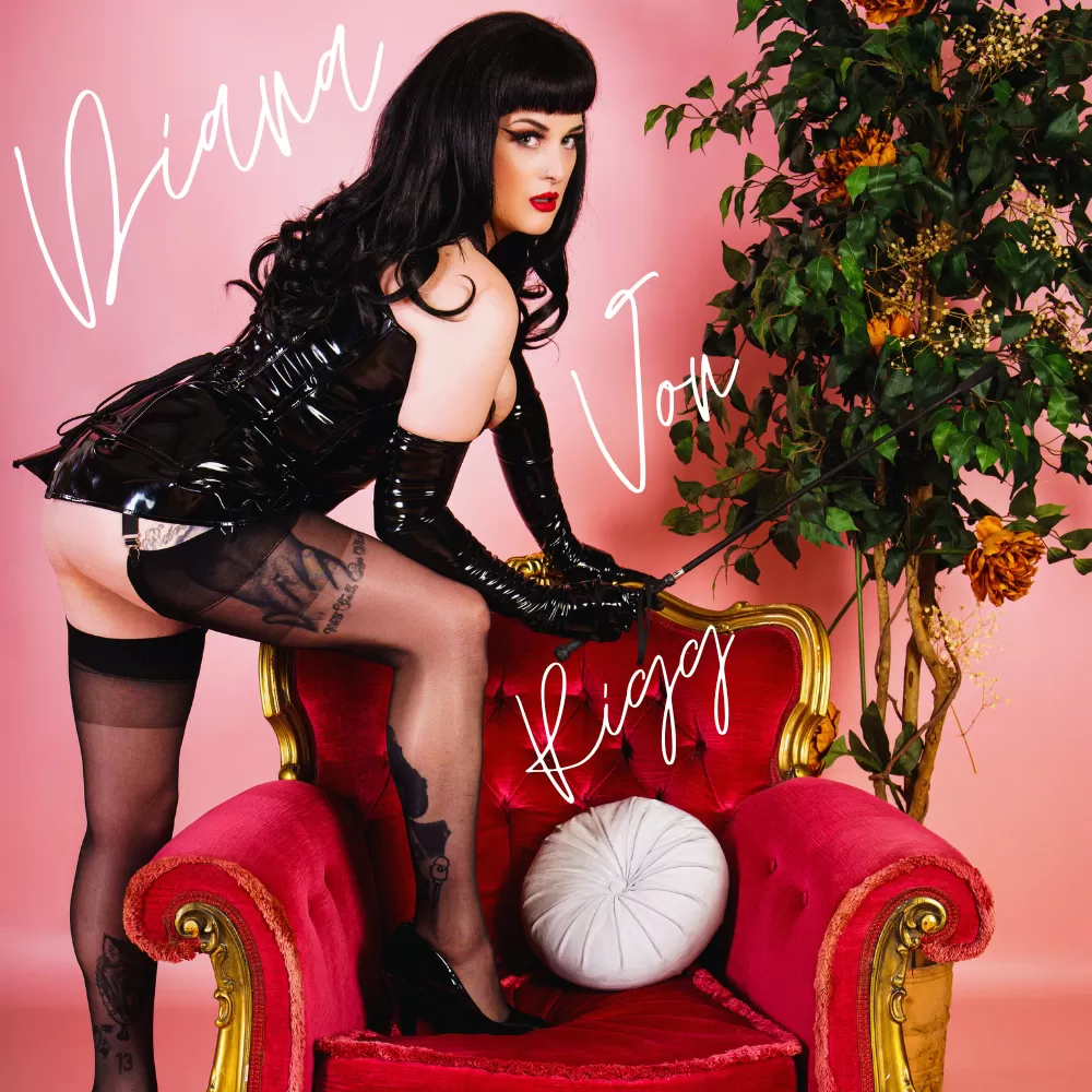 Diana Von Rigg, UK Dominatrix, in latex and stockings on an antique armchair